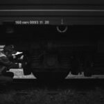 a black and white photo of a man working on a train