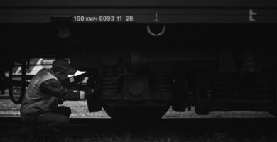 a black and white photo of a man working on a train