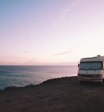 RV parked beside the edge of island during sunset